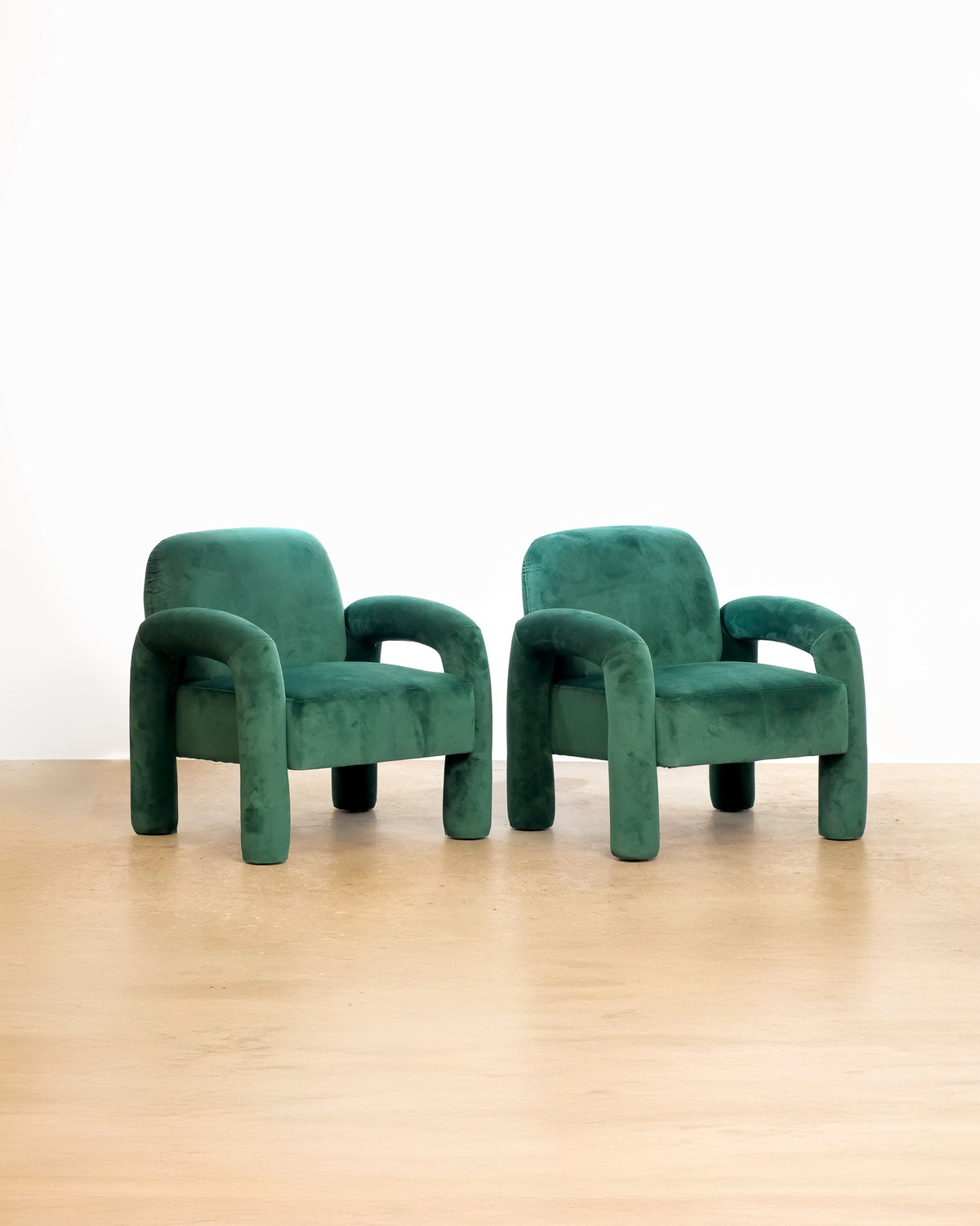 Velvet upholstered emerald green armchair on a plain white background — sculptural mid-century-inspired frame