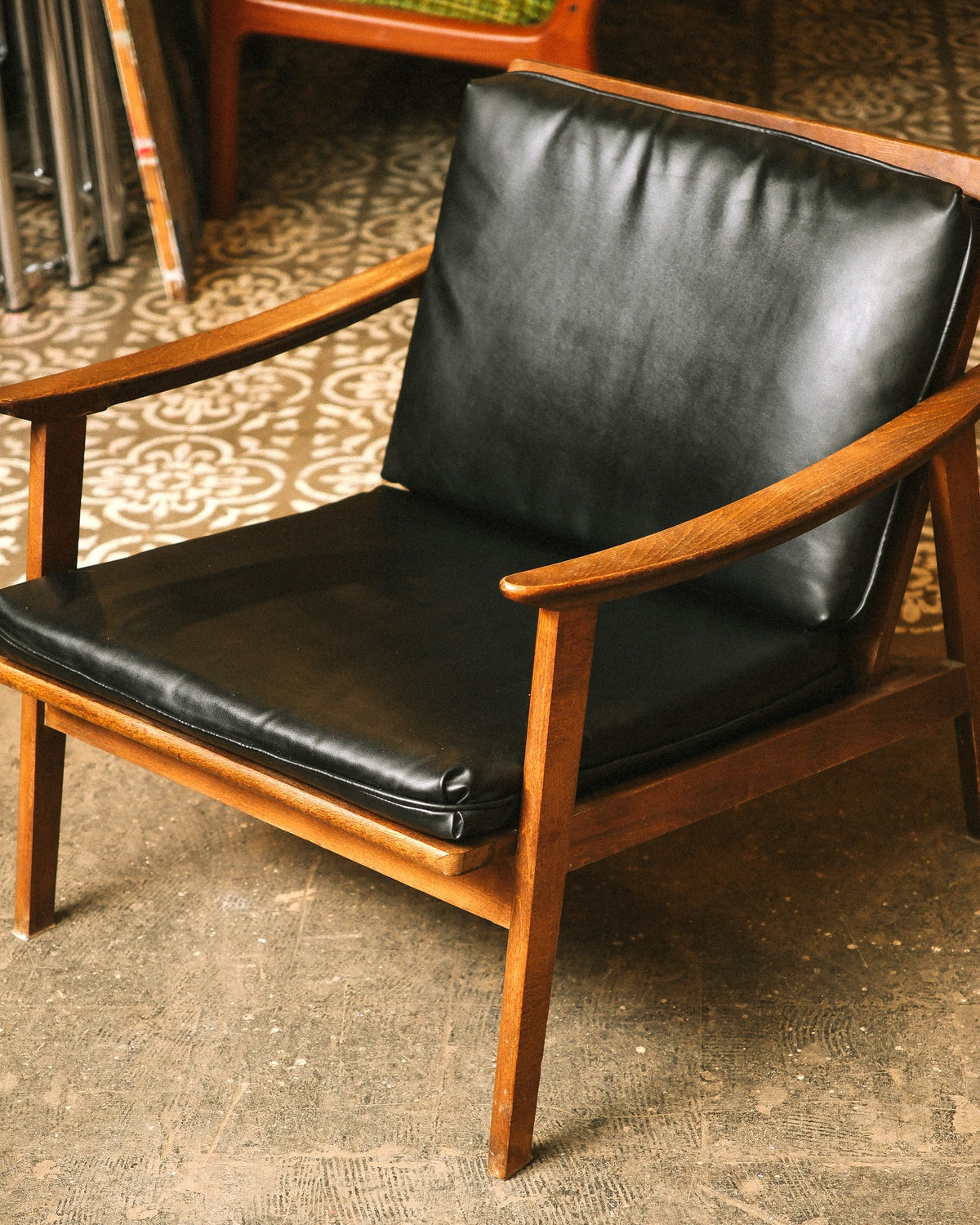Front view of the lounge chair showing the open arm design and black vinyl upholstery.