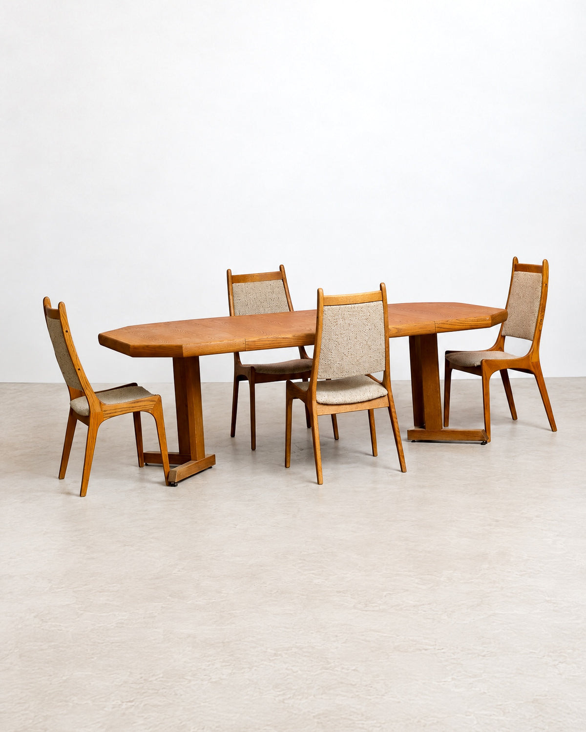 Full view of the extended oak dining table with leaves in place and four chairs.