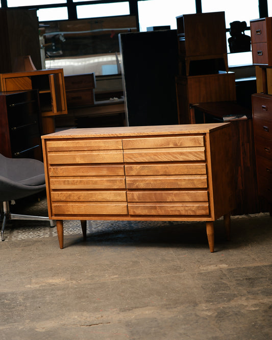 Wooden dresser in a storage or warehouse setting with other furniture items.