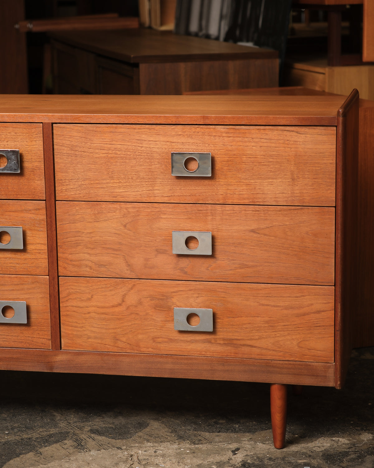 Close-up of three drawers with chrome knob pulls and visible teak grain.