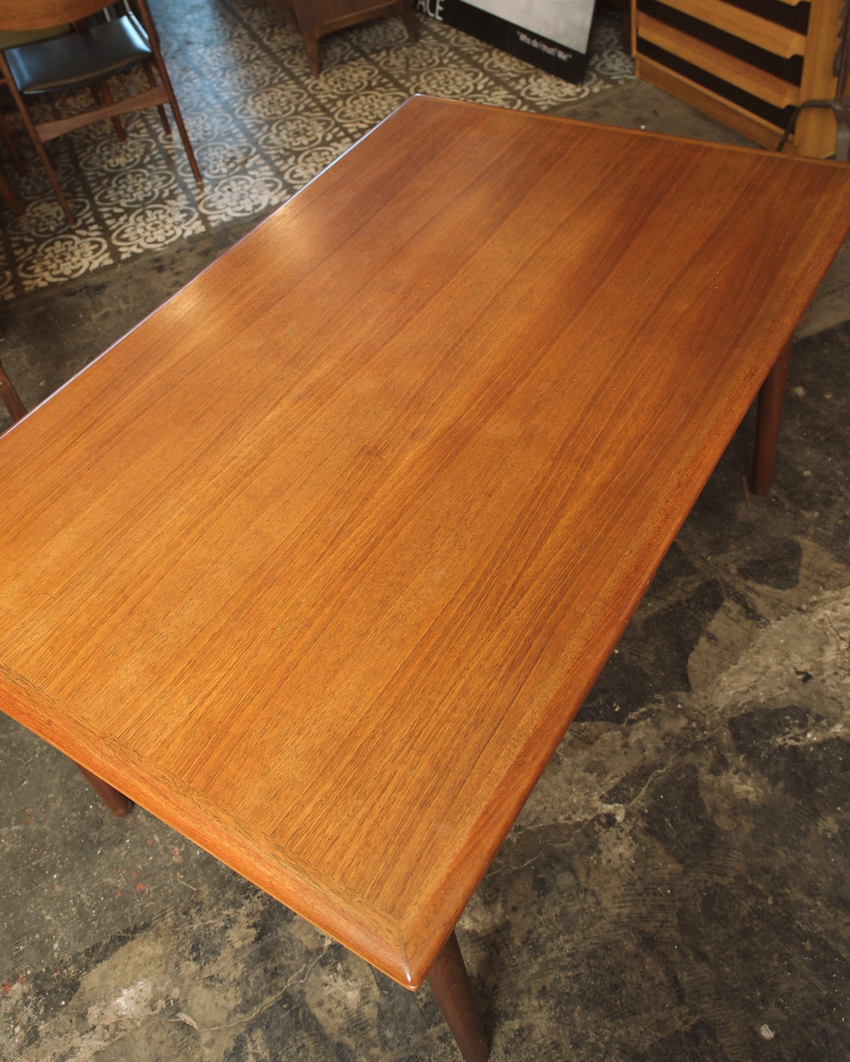 Overhead angled view of the extended teak tabletop and legs in the showroom.