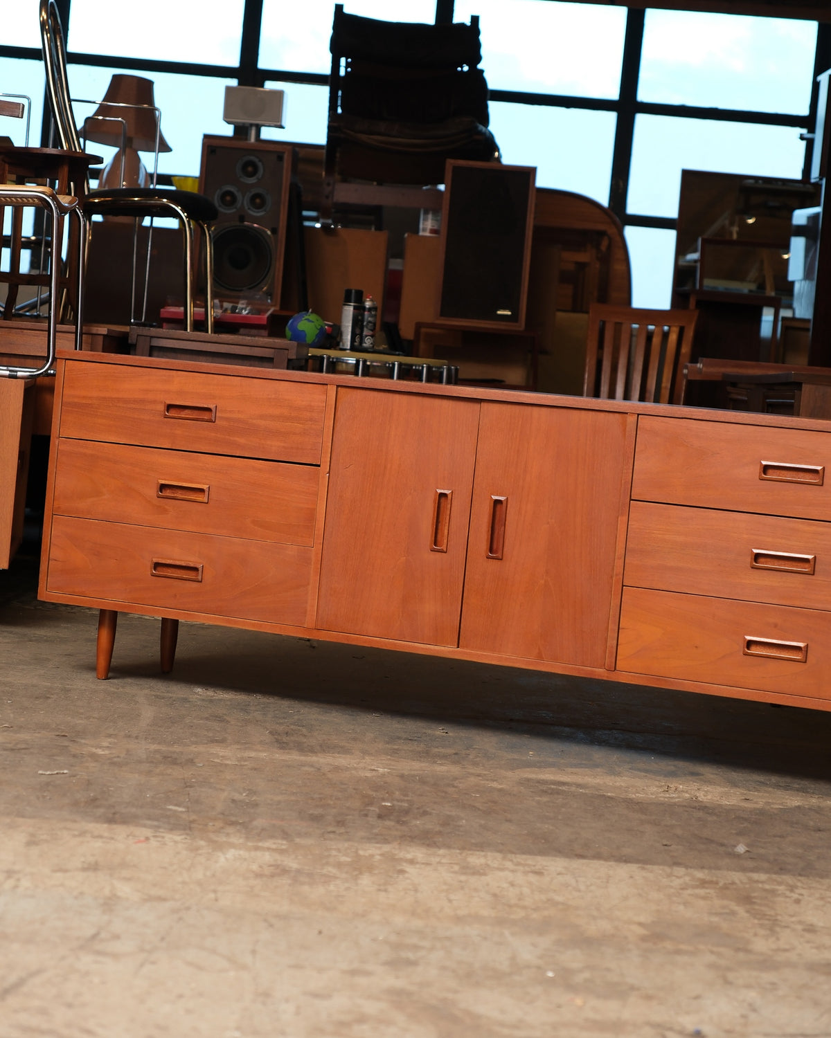 Front view of the teak sideboard showing three drawers on each side flanking a central two-door cabinet.