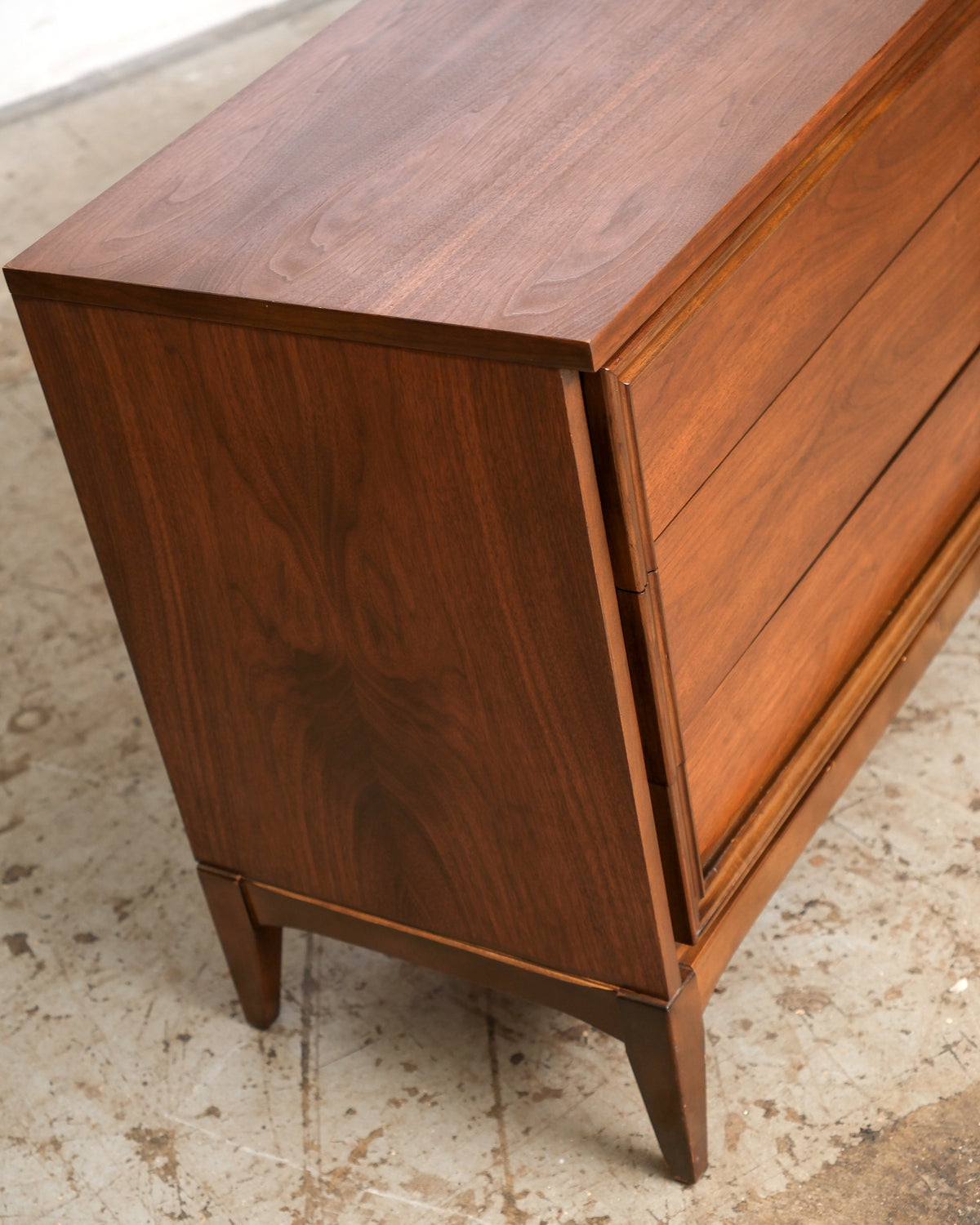 Side view of the dresser highlighting the tapered leg and book-matched walnut grain panel.