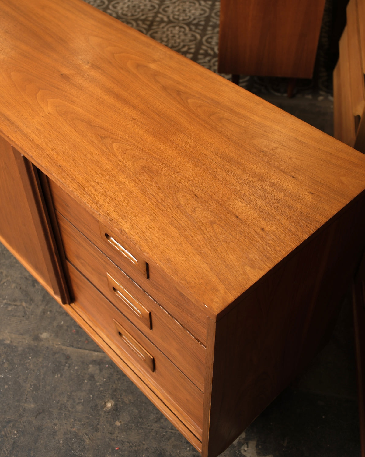 Close-up top view of the drawer pulls and wood grain detail near the corner of the sideboard.