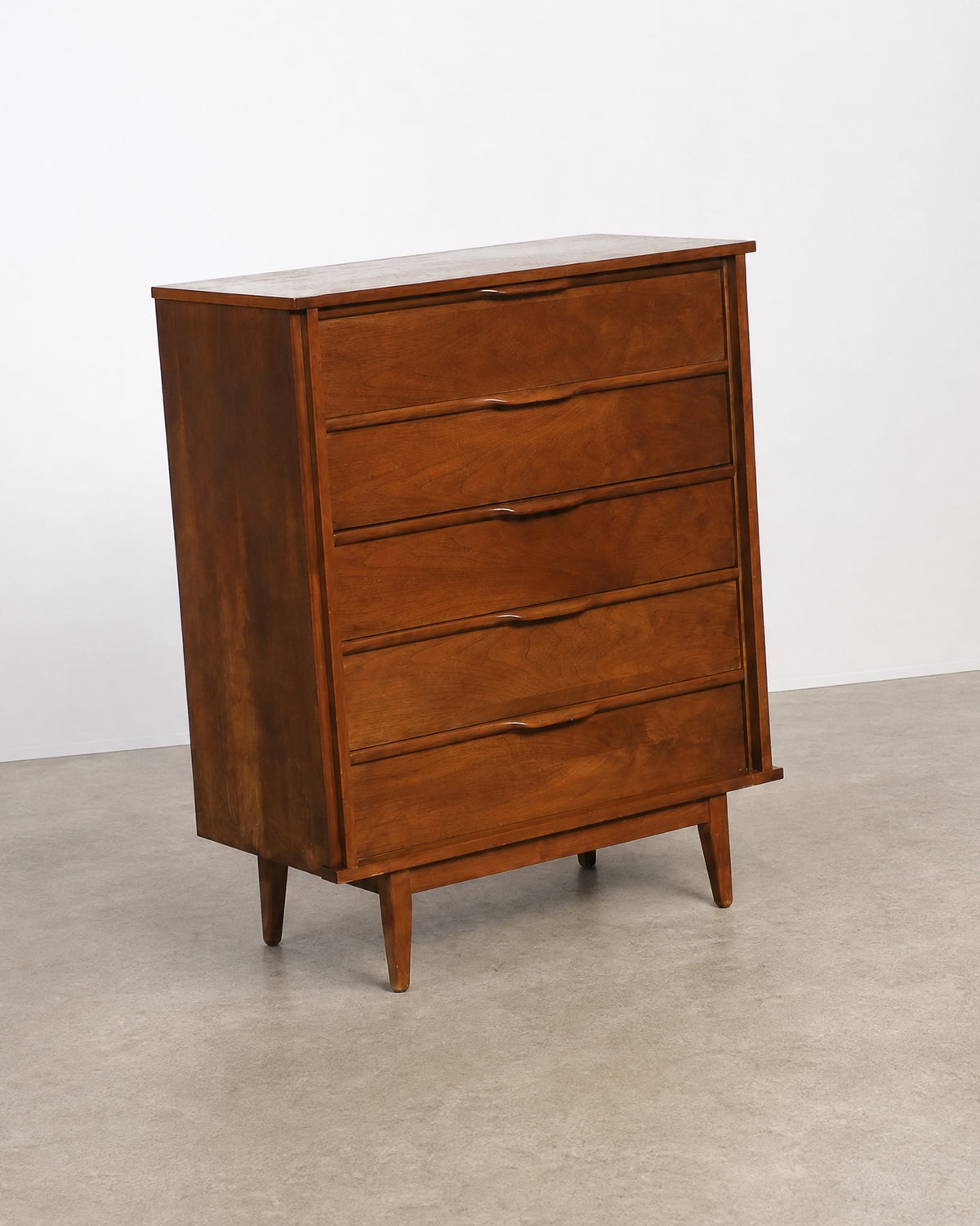Three-quarter angle view of the walnut tallboy dresser showing side profile and tapered legs.
