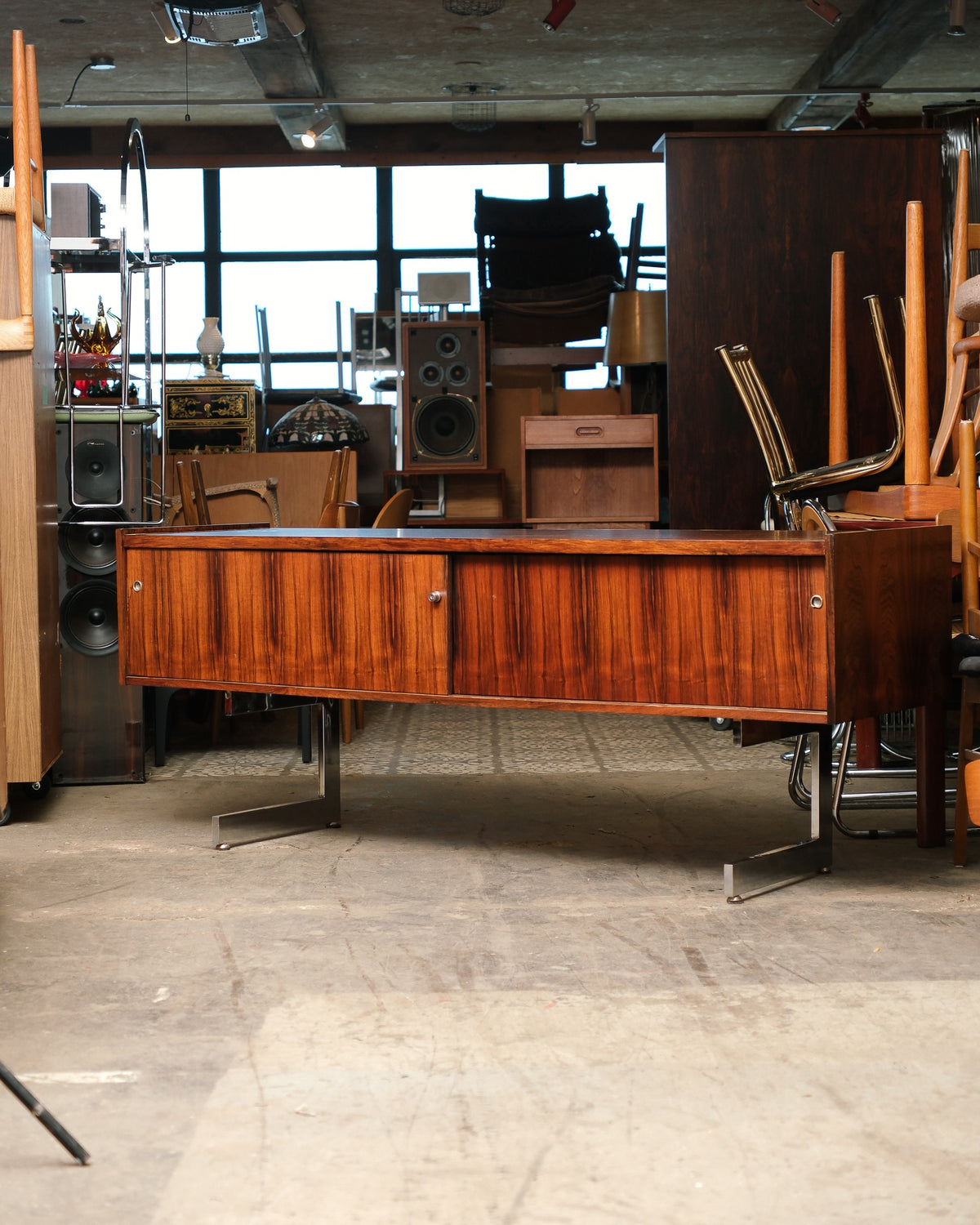 Side view of the rosewood credenza showing its full length and angled chrome leg design
