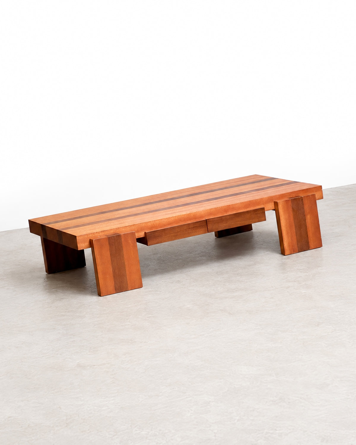 Angled view of a vintage structural coffee table with striped wood top and chunky block legs.