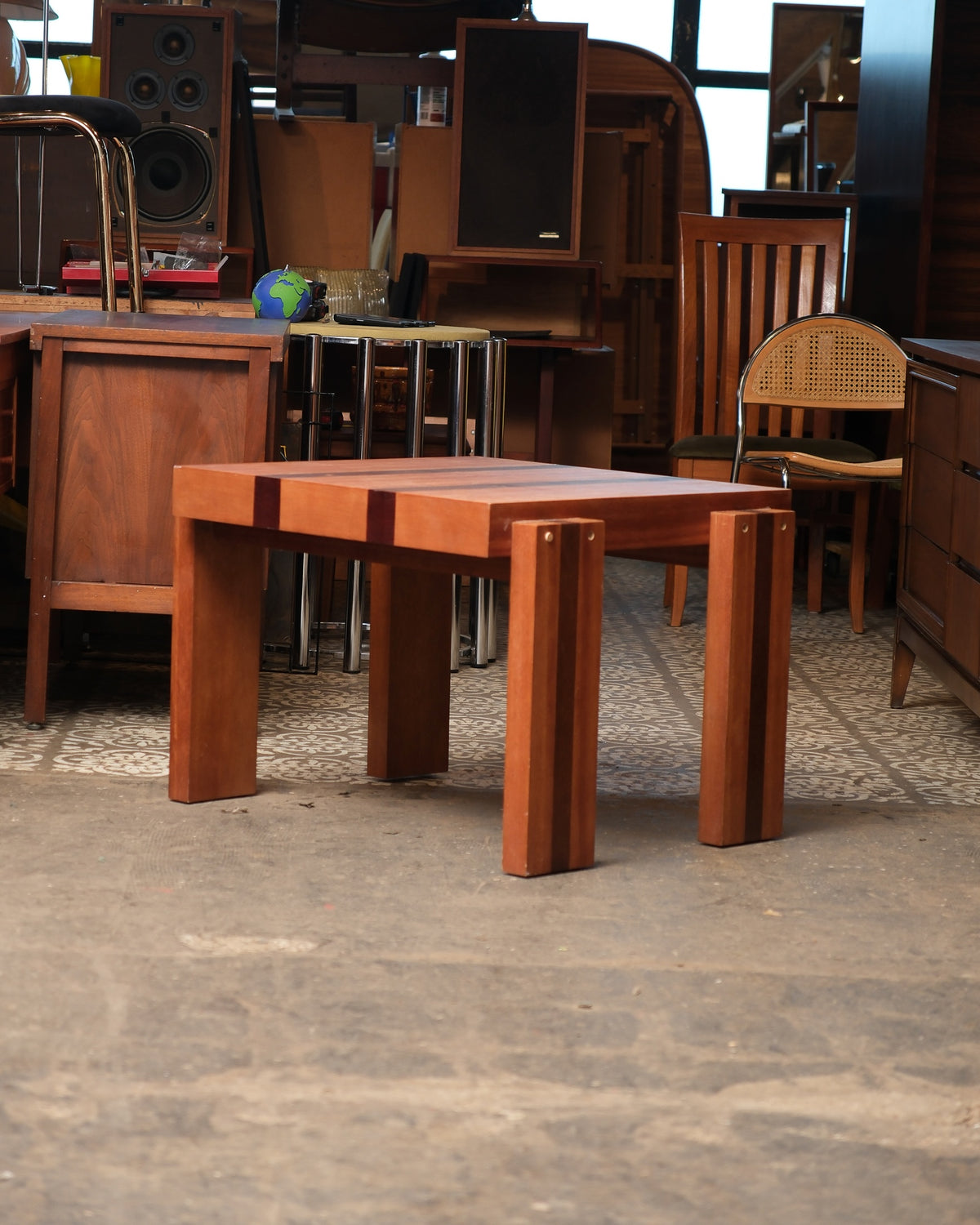 Vintage square coffee table shown in a furniture showroom setting among other pieces.