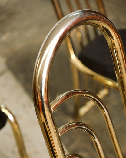 Close-up of the curved brass backrest showing the fanned tubular design and polished finish.
