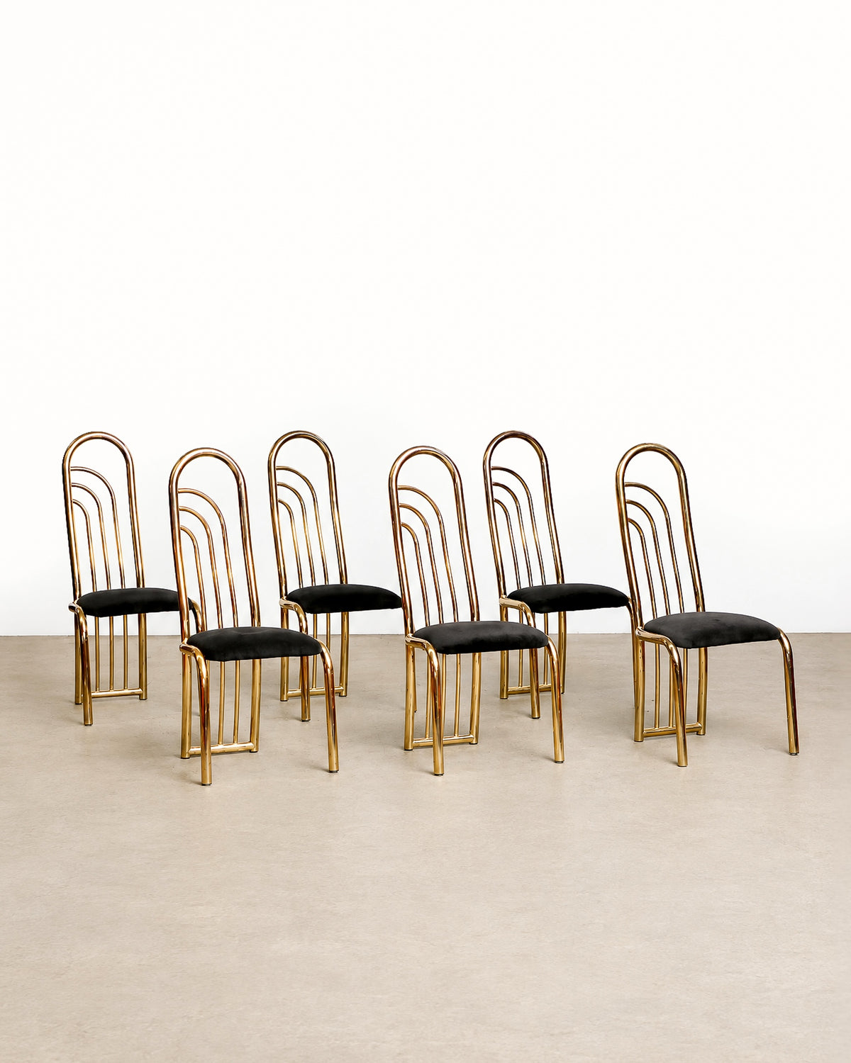 Wide view of several brass chairs arranged together showing the matching set.