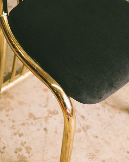 Detail of the brass leg and seat join showing the tubular frame and velvet upholstery.