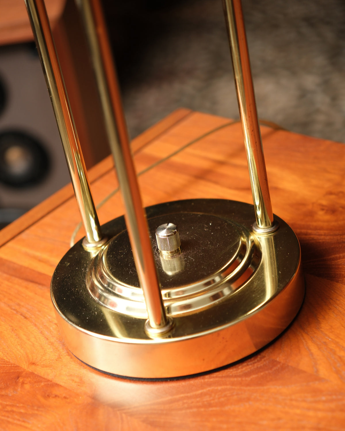 Close-up of the lamp base showing three brass rods and the knurled dimmer knob.
