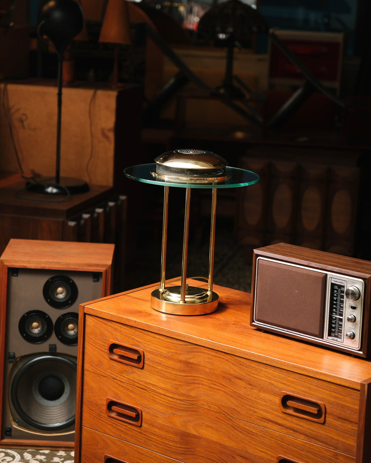 Brass saturn lamp displayed on a teak dresser next to a vintage radio, shown lit.