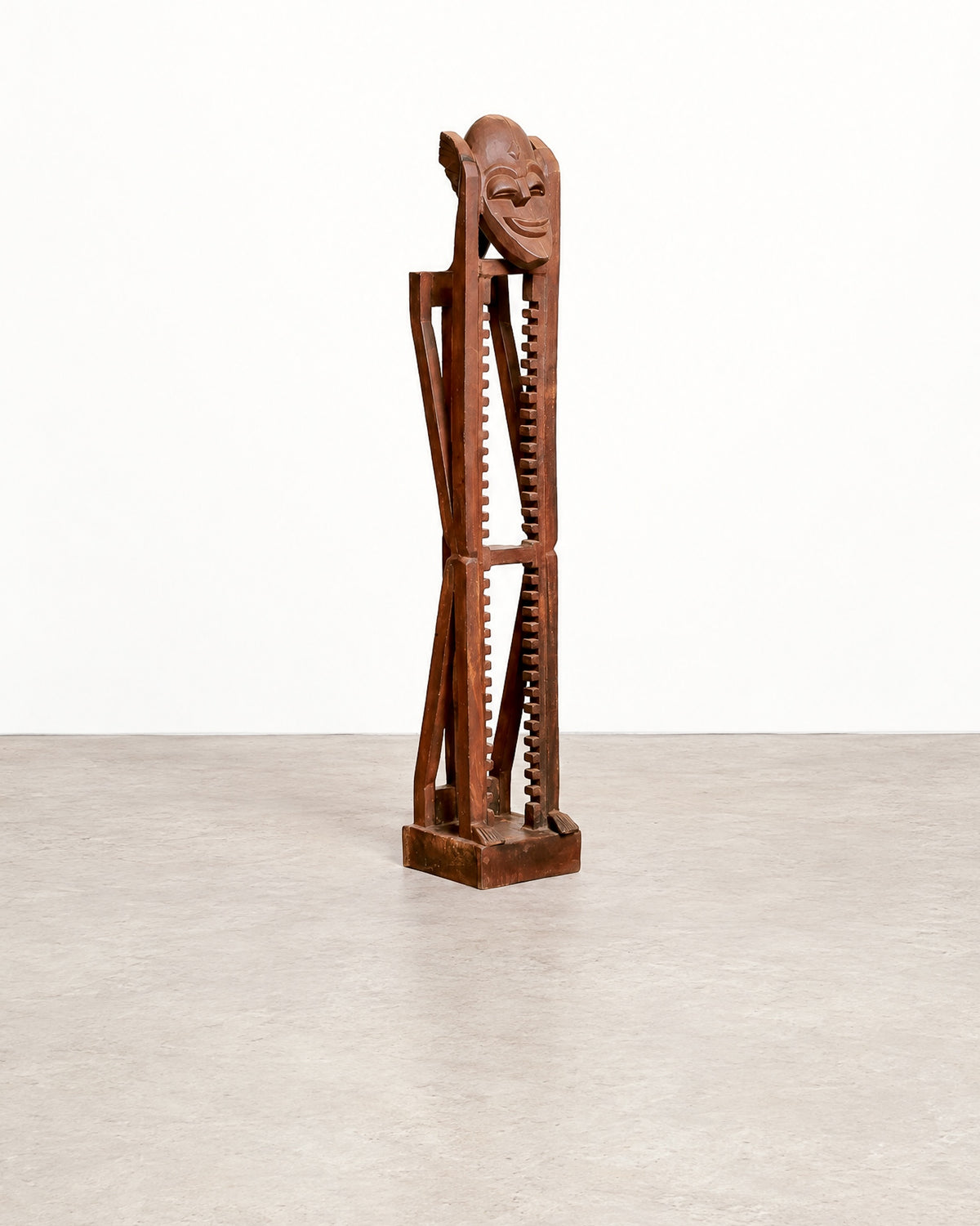 Full straight-on view of the brutalist mask tower against a plain backdrop, showing its full height and square base.