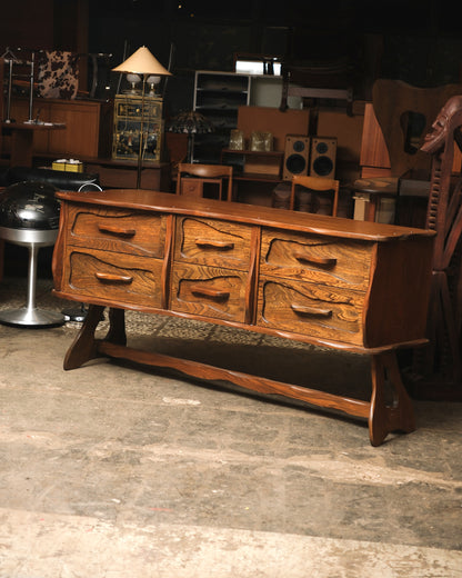 Angled front view showing the carved drawer fronts and sculpted pulls of the oak dresser.