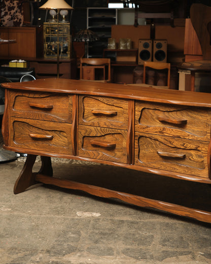 Close front-on view of the six upper drawers with wave-carved detailing and sculpted wood pulls.