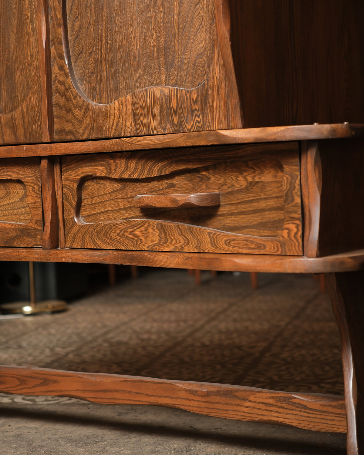 Close-up of a carved drawer handle and door panel detail, showing oak grain and joinery.