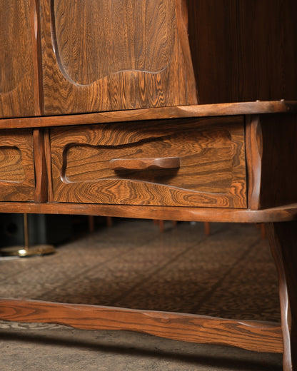 Close-up of a carved drawer handle and door panel detail, showing oak grain and joinery.