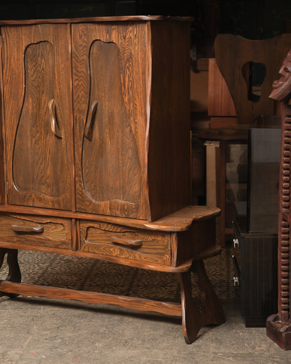 Front corner view of the cabinet showing both doors, drawers, and the trestle base leg.
