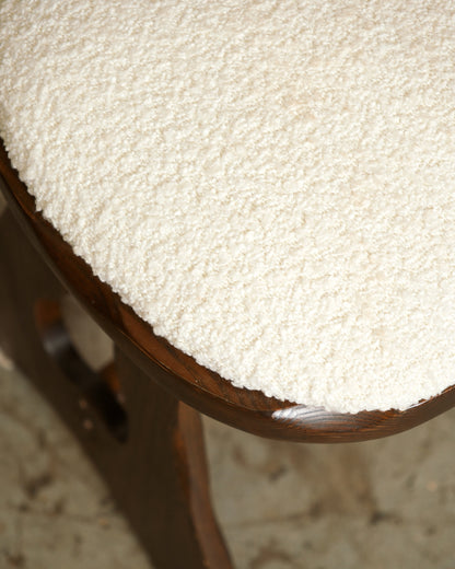 Close-up of a boucle-upholstered chair seat and solid oak frame with visible wood grain.