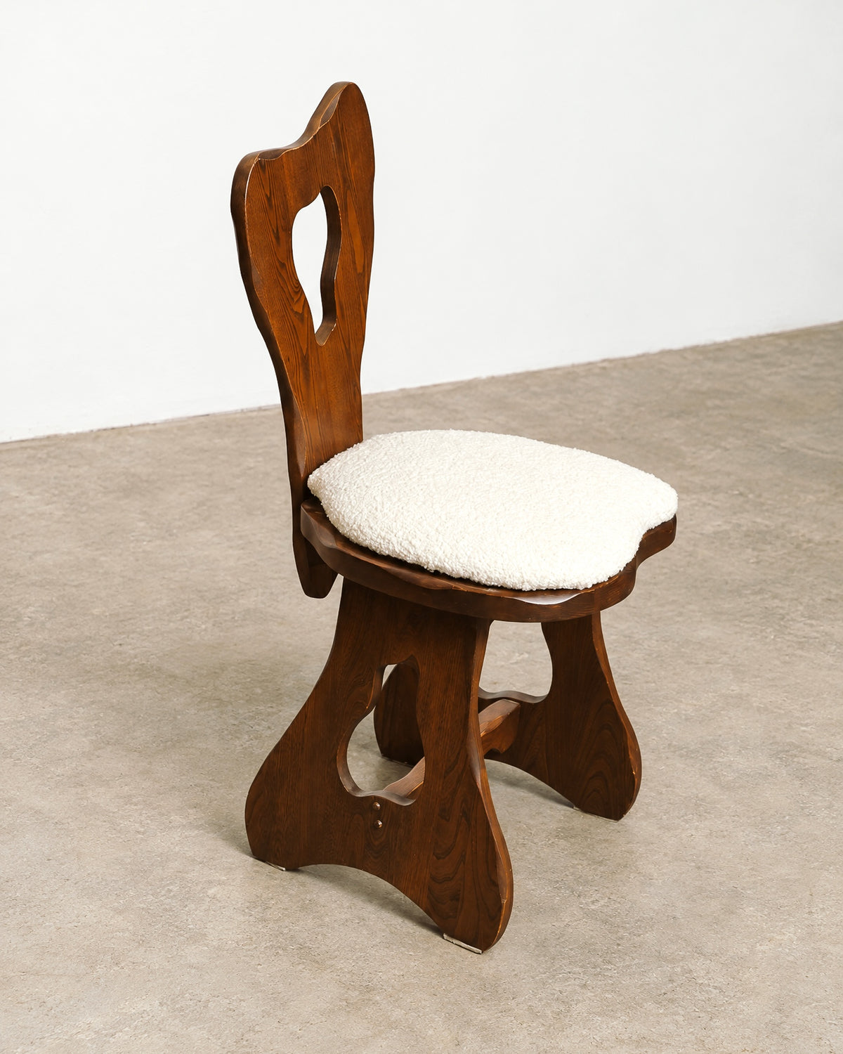 Close-up of a boucle-upholstered chair seat and solid oak frame with visible wood grain.