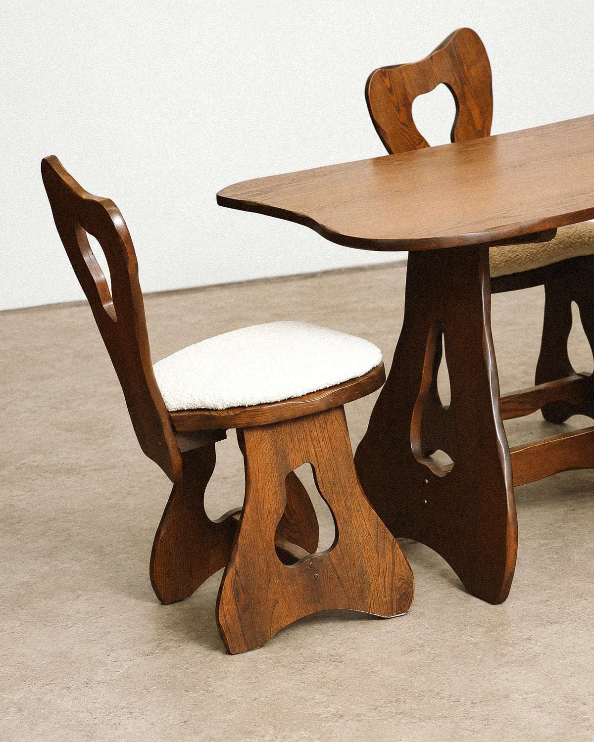 Close-up of a boucle-upholstered chair seat and solid oak frame with visible wood grain.