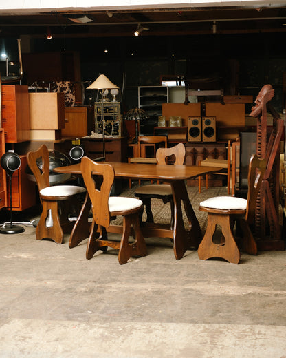 Side view of the dining set showing the trestle-style table base and swivel chair seats.