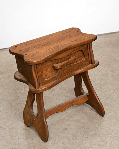 Additional angle of the nightstand showing the carved drawer front and leg joinery.