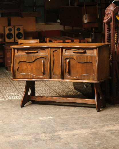 Three-quarter view of the brutalist oak sideboard on its shaped trestle base.