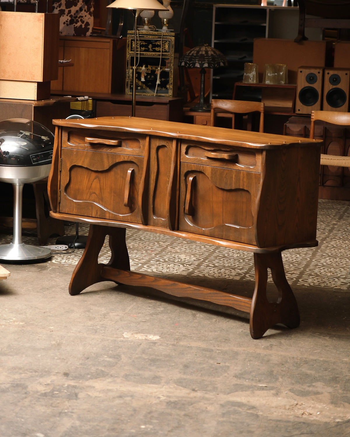 Side angle of the oak sideboard highlighting the wave-cut top edge and carved handles.