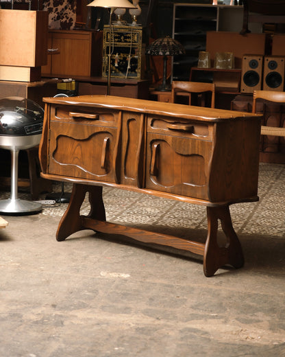 Side angle of the oak sideboard highlighting the wave-cut top edge and carved handles.