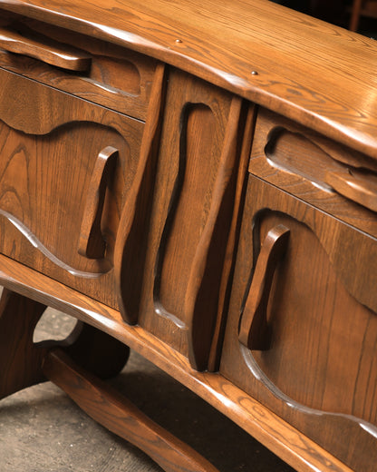 Detail of the carved door panels and drawer pulls along the front of the sideboard.