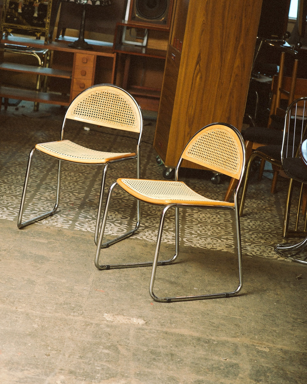 Two vintage cane chairs with chrome frames shown side by side in a showroom setting