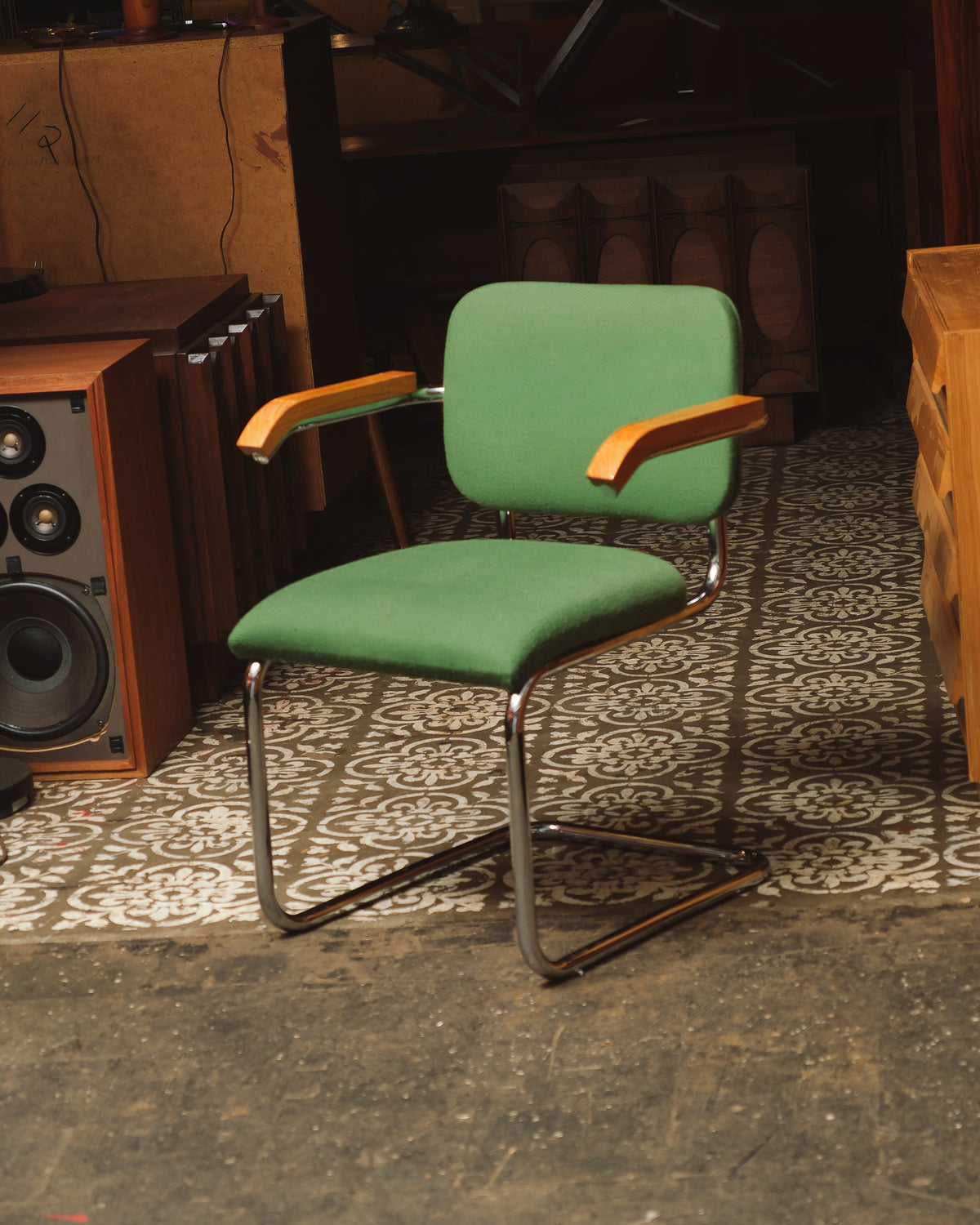 Front angle view of the Cesca-style chair with green fabric and chrome frame, shown in a vintage furniture showroom.