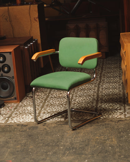 Front angle view of the Cesca-style chair with green fabric and chrome frame, shown in a vintage furniture showroom.