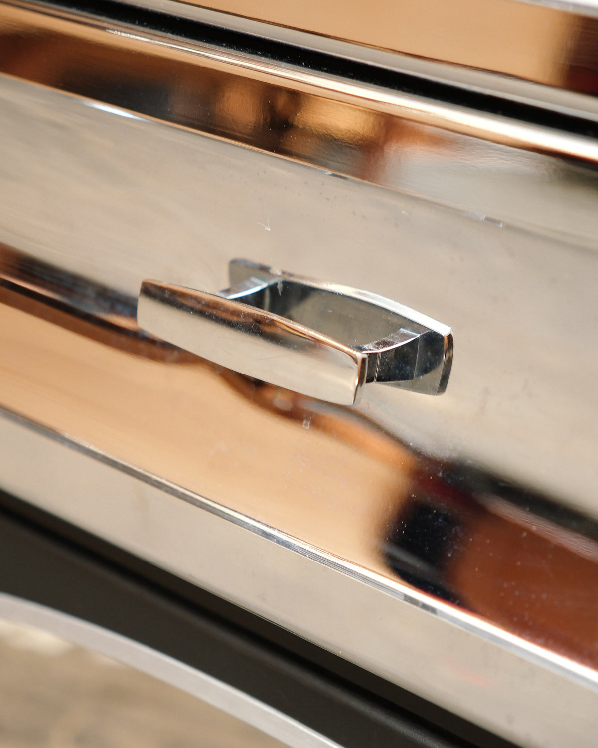 Close-up of the chrome drawer pull and reflective drawer front.
