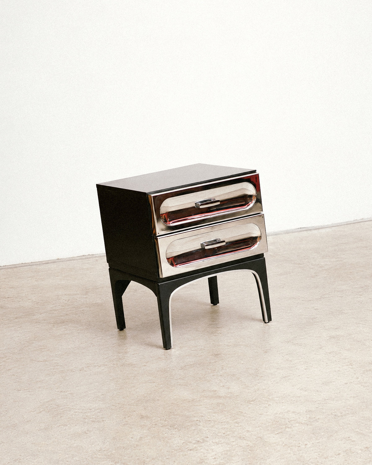 Studio angled view showing the top, chrome drawers, and arched leg detail.