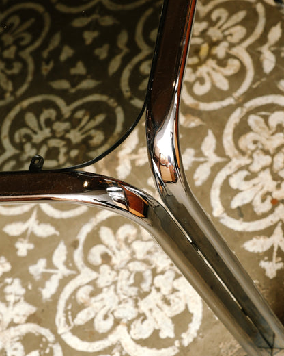 Close-up of the chrome tubular leg joinery and glass edge on the vintage coffee table.