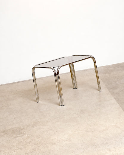 Side angle view of the chrome coffee table showing its splayed leg design and glass top.