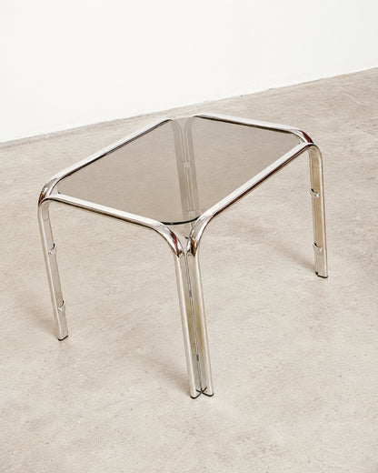 Three-quarter view of the chrome coffee table highlighting its sculptural leg structure.