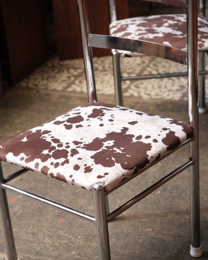 Detail view of the cowhide print upholstery and chrome frame joinery on the seat.