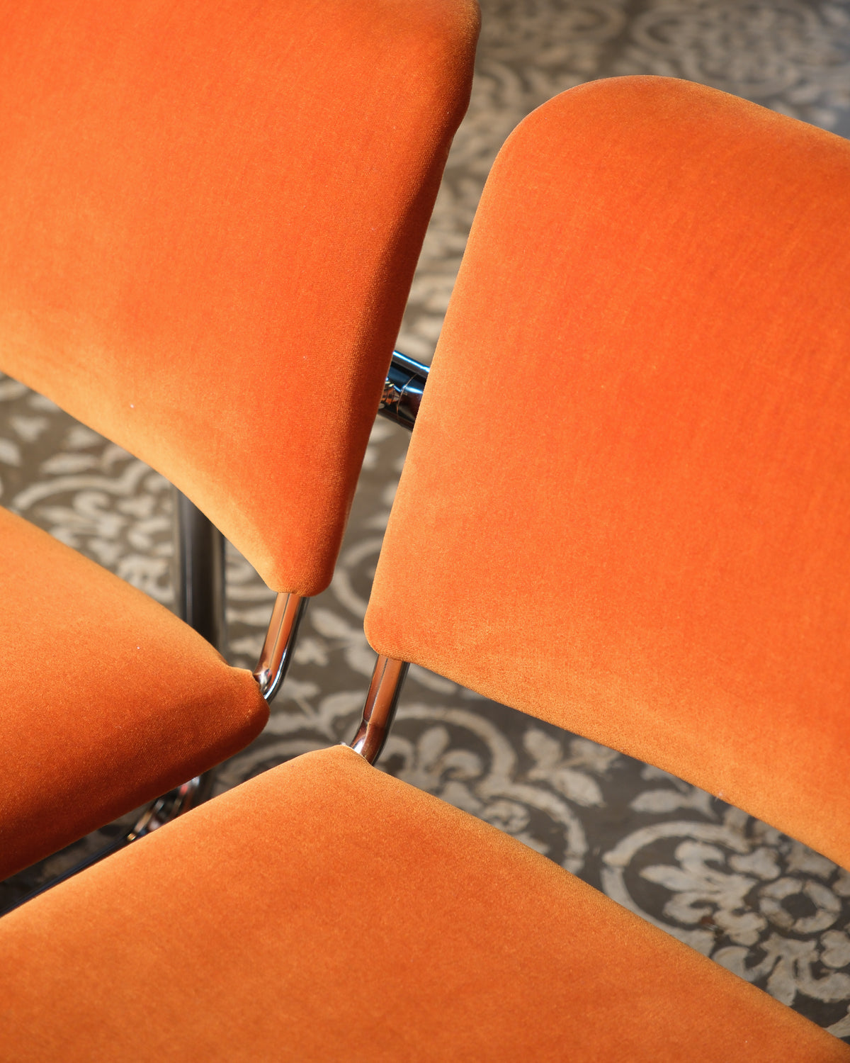 Overhead detail of stacked orange tubular chairs showing chrome frame connections.