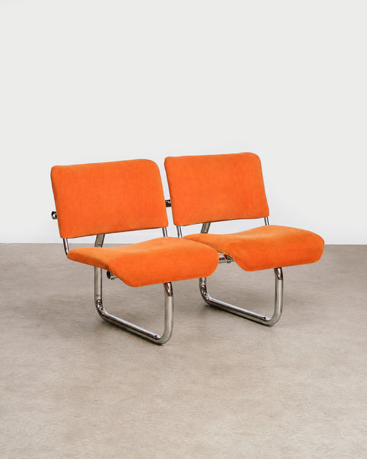 Close-up of the chrome frame detail on an orange tubular chair.