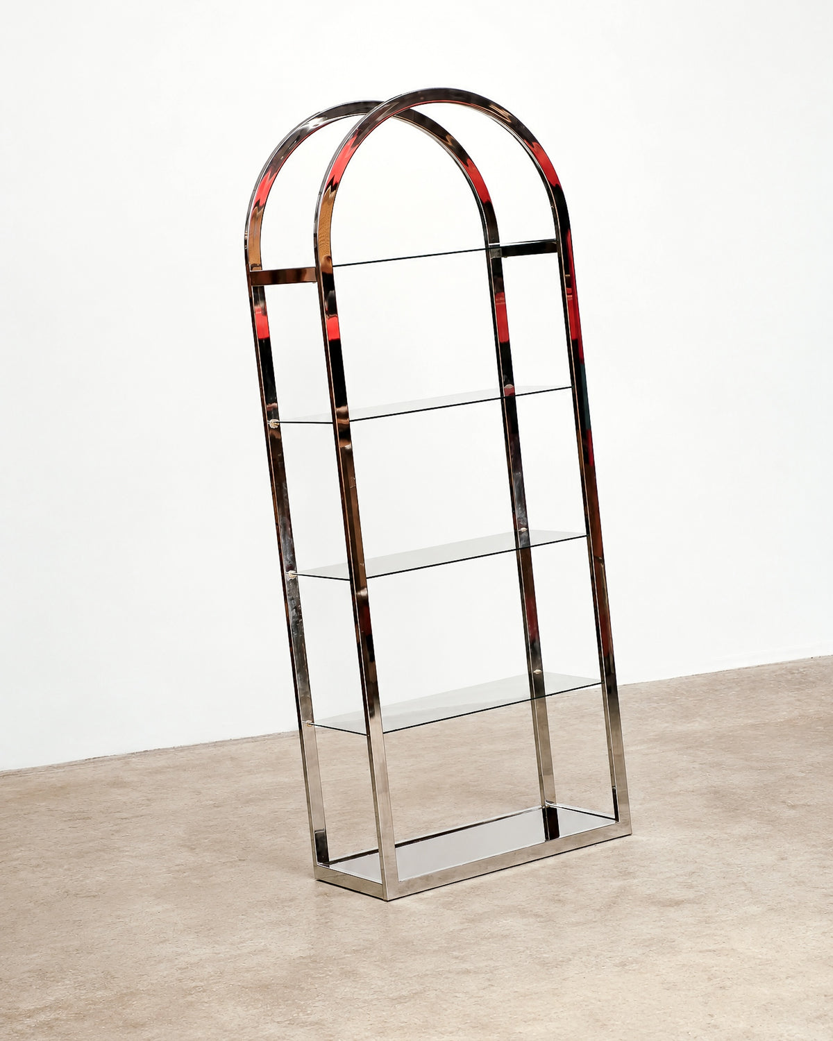 Front angled view of the chrome arched étagère with four smoked glass shelves against a plain backdrop.