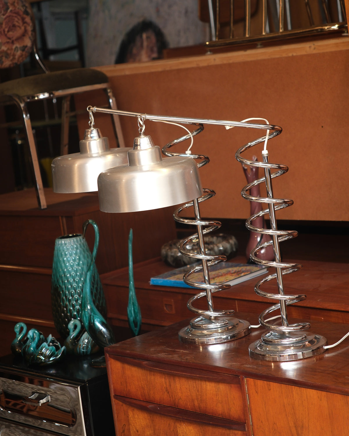 Two matching chrome spiral lamps side by side atop a mid-century cabinet
