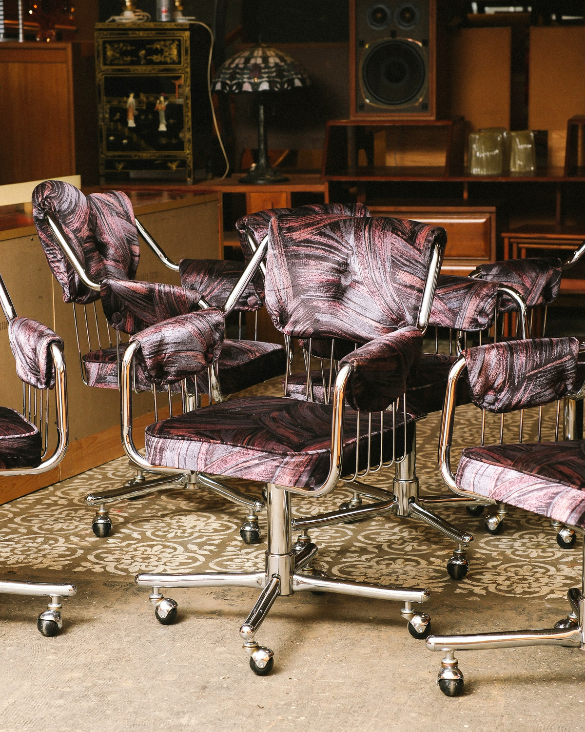 Side view of chrome swivel armchairs clustered together showing tufted backs and casters