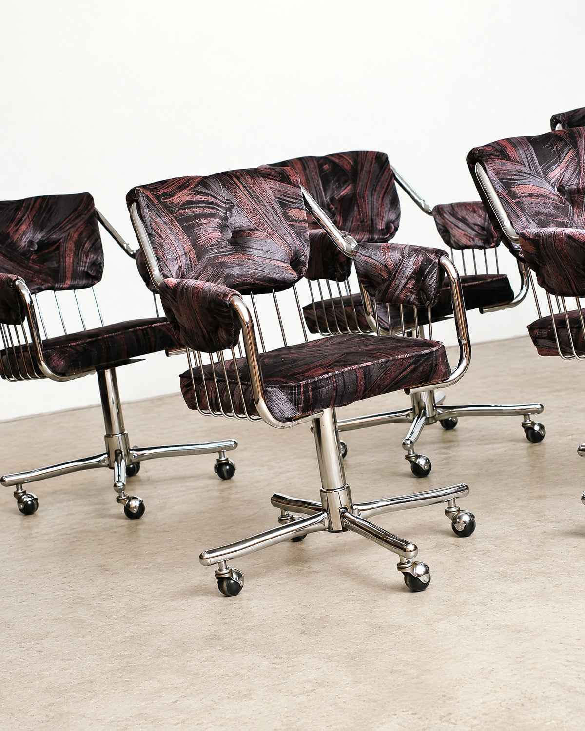 Front view of a single chrome swivel rolling armchair showing armrests and caster base