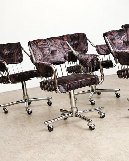 Front view of a single chrome swivel rolling armchair showing armrests and caster base