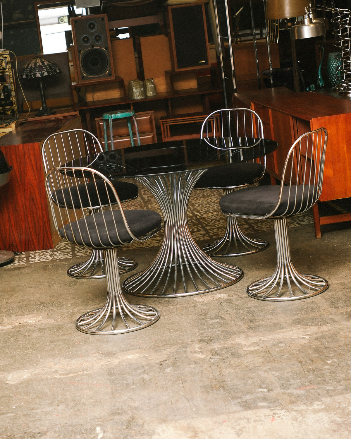 Full view of the chrome Tulip "Margot" dining set with oval glass top and four swivel chairs.